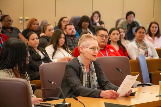 Marina Khalina reads from a proclamation at the dais of the Multnomah County boardroom.