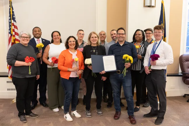 The Board of Commissioners stands with a group of people and hold up a signed proclamation.