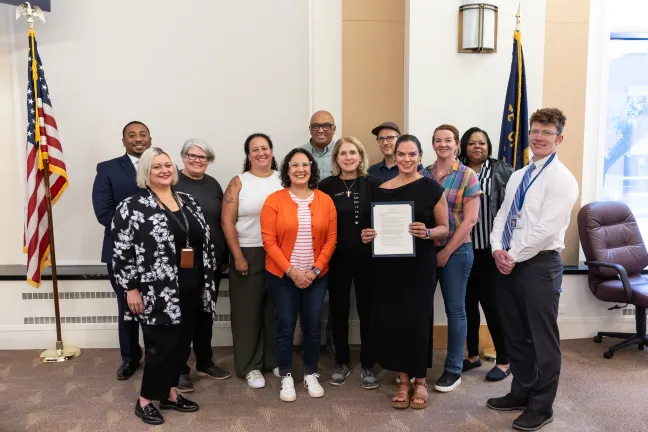 The Board of Commissioners poses with a group of people holding up a signed proclamation.