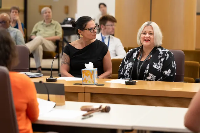 Denis Peña and Ansley Flores sit at the dais in the Multnomah County Boardroom.