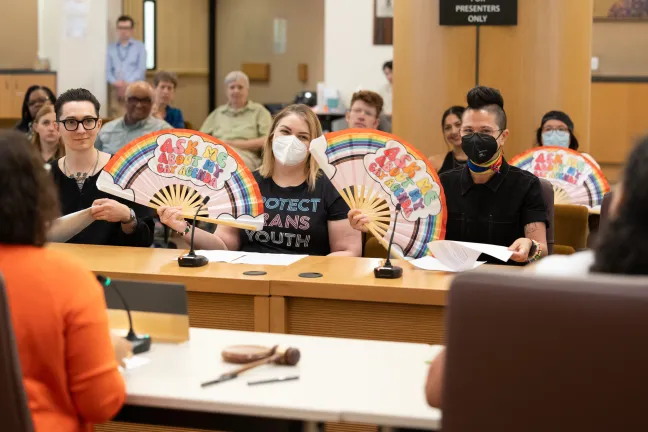 (From left) County employees Gabriel Hernandez, JB, and Sam Silverman read the proclamation for Pride Month.