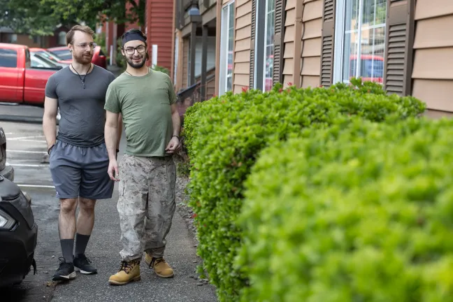  A low-angle full-shot of two men walking side-by-side on a sidewalk.