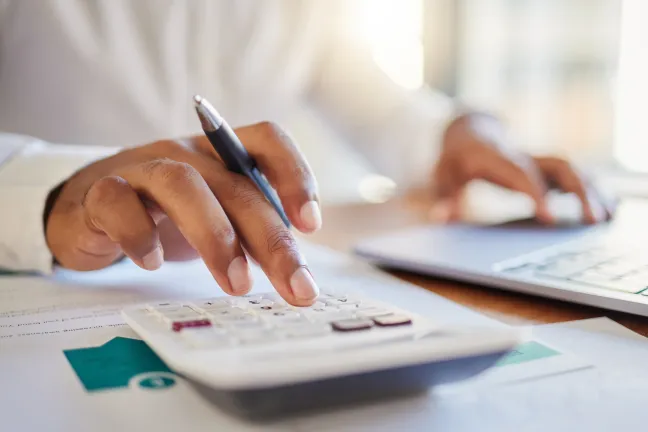 A businessman works out his budget on a computer and calculator