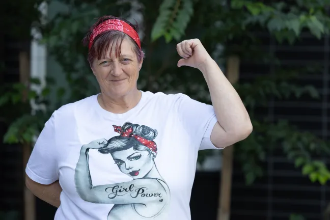 April smiles and holds her arm up as if she is flexing her arm.