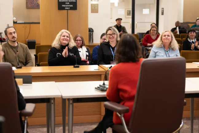 Four presenters seated before the Board. 