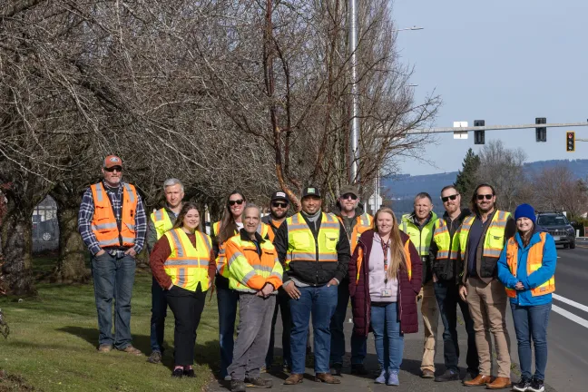 Group of people posing next to the road in high vis safety vests