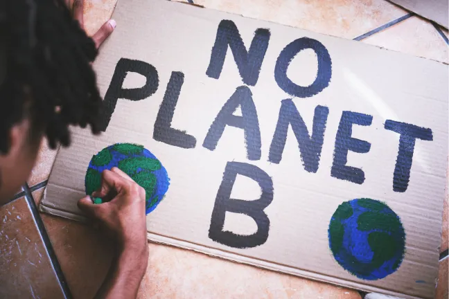 Boy creating poster that says "No planet B"