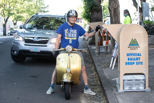 voter on moped returns ballot at drive up official ballot drop site location