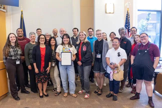 Board members, County staff and invited guests pose with the signed Older Americans Month proclamation in the boardroom.