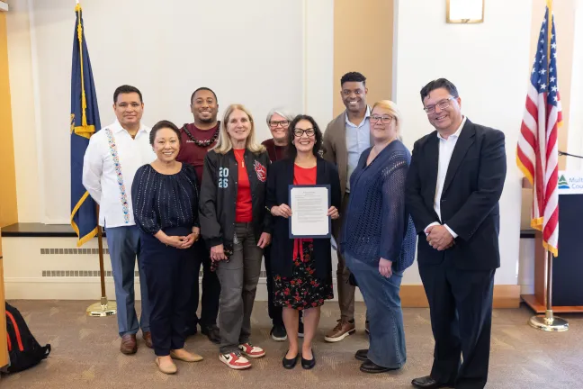 Board members, County staff and invited guests pose with the signed Community Action Month proclamation in the boardroom.