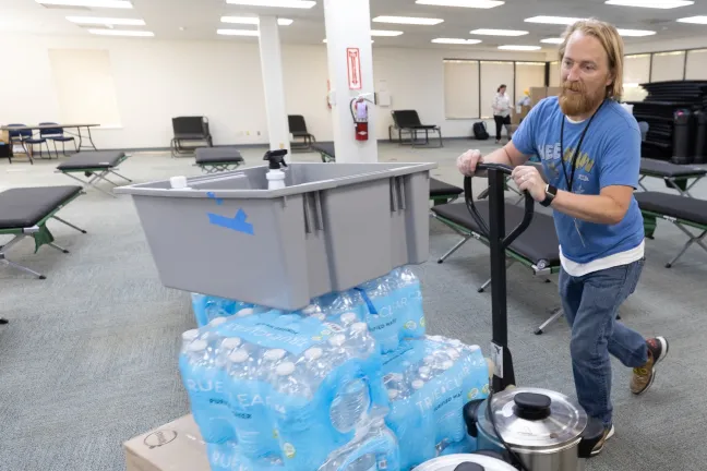 A County employee moves a pallet of bottled water and coffee percolators inside a cooling center.