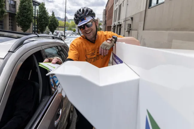 A bicyclist drops off their ballot at an Official Ballot Drop Site near the Multnomah County Elections Building. 