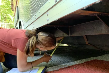 A sanitarian inspects the underside of a food cart
