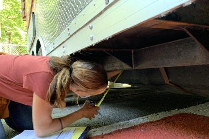 A sanitarian inspects the underside of a food cart