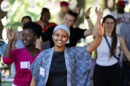 A group of women at a park celebration smile and wave
