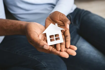 A person's hands carefully cradle a toy shaped like a house