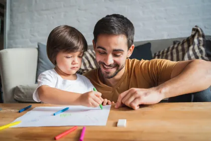 A parent and child working together on a math activity at their coffee table at home. 
