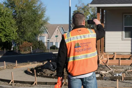 Appraiser in orange vest works in a neighborhood