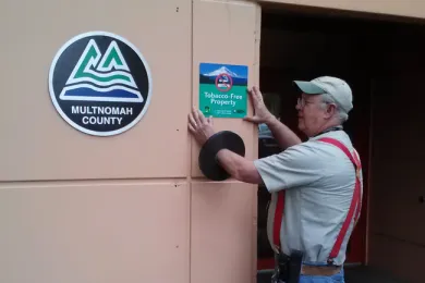 Smokefree sign being installed outside on Multnomah County property
