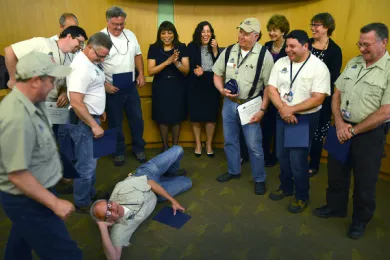 Commissioner Smith, Chair Madrigal, Commissioner McKeel, Commissioner Shiprack and the county's carpenter and locksmith teams look on as carpenter Dennis Rutt poses on the floor during a light moment.