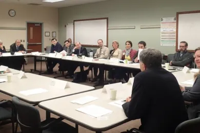 A group of people sit around a table discussing juvenile justice practices. 