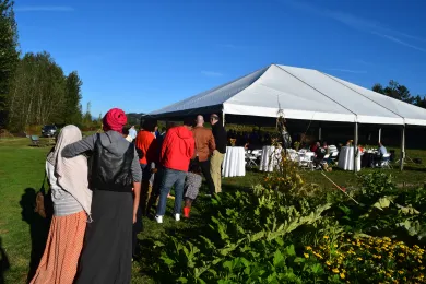 Wide shot of a tented seating area with a line of people waiting for the buffet.