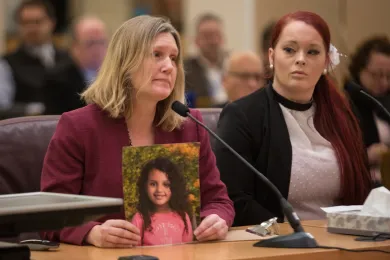 Stephanie Stephens holds up a picture of her daughter at Thursday's board meeting as Lisa Greenfield looks on.