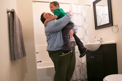 Andrea Bunch holds her son, Michael, 4, in their new bathroom. They moved into an apartment as part of the Home for the Holidays campaign.
