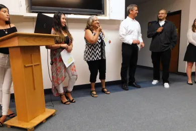 Teresa Campos, center, smiles as her son Jairo Rios-Campos takes the microphone. 