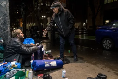 Perlia Bell, an outreach worker with JOIN, offers a tarp to Josh on a street in downtown Portland on Dec. 17, 2018. 
