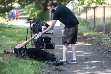 Michael Phelps, outreach worker/case manager, hands out water along with other care items under the record-breaking heat in SE Portland. Cascadia Behavioral Healthcare's Street Outreach Team also offers mental health and housing education.