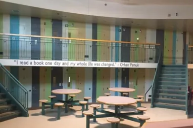 Image of a common area at the Donald E. Long Juvenile Detention Facility. There is a quote painted on the balcony that says, "'I read a book and one day my whole life was changed.' - Orhan Farmuk"