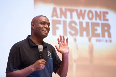 Antwone Fisher stands on stage to share his story with POIC + Rosemary Anderson High School and Multnomah County staff.