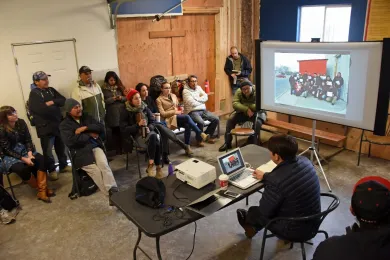 Group of people sitting on park bench in a building listening to a presentation