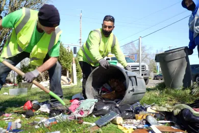 A photo of men wearing vests and cleaning garbage