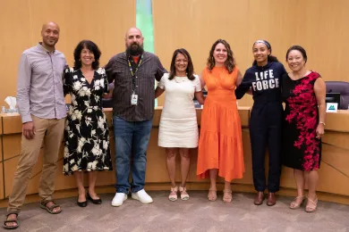 Members of the board, staff from the Multnomah County library and Multnomah Education Service District and Esparanza Spalding pose for a photo in front of the dais in the Multnomah County boardroom.