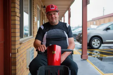 A man in a mobility scooter wearing a red hat.
