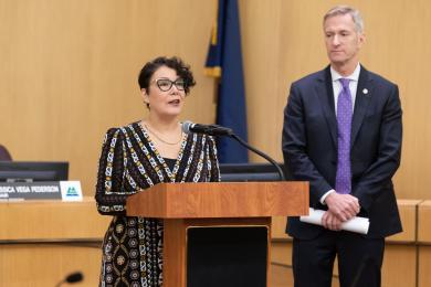 Jessica Vega Pederson stands at a dais next to Mayor Ted Wheeler