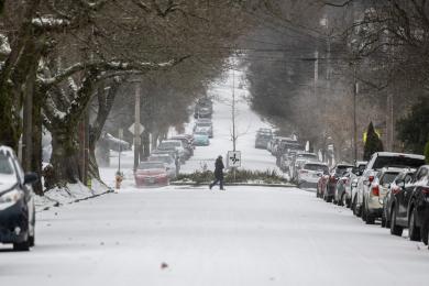 A photo of a snowy road with a person walking in the background