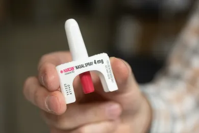 A hand holding Narcan nasal spray