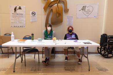 Three volunteers work at a cooling center check-in desk