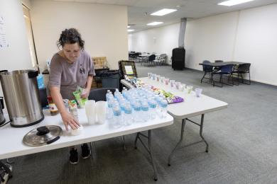 A person arranges water bottles at a table in an indoor cooling center.