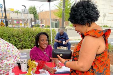 Charlene McGee helps with sign ups and token distribution for a community-supported agriculture program during recent REACHing US: People's Market in Rockwood