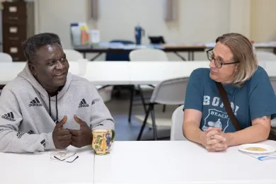 Two people sit at a table and talk to each other