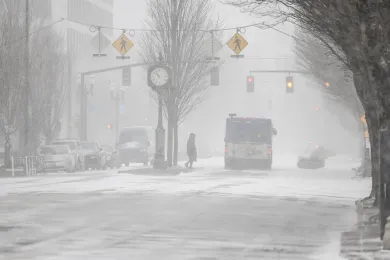 Bus and person walking in Portland street while it snows