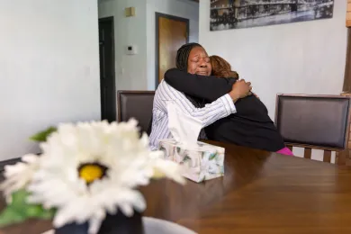 Two women embracing at a table.