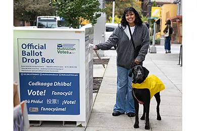 Woman drops off ballot at Official Ballot Drop Site.