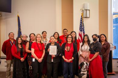 The Board of Commissioners poses with employees and community members, all wearing red.