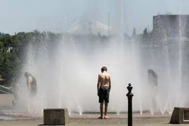 Children stand in an interactive fountain on a sunny day.