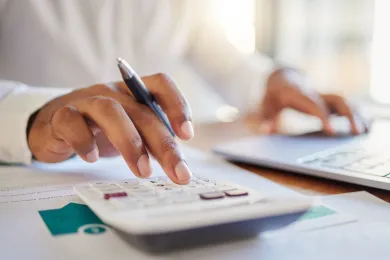 A businessman works out his budget on a computer and calculator